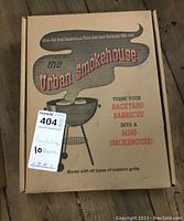 Photo of closed Urban Smokehouse branded cardboard box showing product label and usage claim 'Turns your backyard barbecue into a mini-smokehouse'.