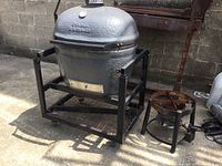 Full view of grey ceramic Primo Kamado smoker on black metal rolling cart
