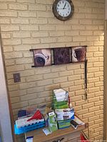 Overview photo of assorted items on top of wooden surface against a beige brick wall, showing the collection of cleaning and kitchen supplies.