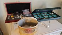 Wide view of black and blue jewelry boxes on a table and a round gold-tone storage container in front