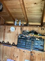 Wide view of wooden wall with multiple Stanley jack planes lined on a shelf, plastic hardware storage bins beneath, and miscellaneous tools and containers on top shelf.