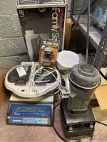 Lot contents including Vitamix blender, Jadever counting scale, Toastmaster griddle box, Climbotron toy, Mr. Coffee maker, and Pur Steam steamer.