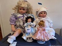 Four porcelain dolls displayed together, showing height range and clothing styles.