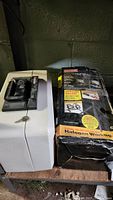 Side view of white Sentry Safe next to boxed Craftsman halogen work light.