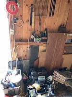 View of tool shed wall with various tools, supplies, boxes, tool boxes and wiring scattered on floor and shelves