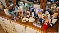 Dresser top with multiple trinket dishes, numerous beauty product bottles, lotions, and perfumes arranged among decorative items.