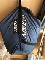 Blue storage bag of an AeroBed inflatable air mattress with carrying straps and logo visible.