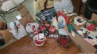Overview of the Christmas decorations and wrapping materials spread on the floor with bags and a cardboard box containing various festive items
