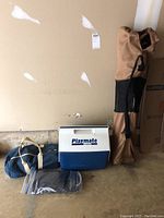 Overview of all items: cooler, bocce ball set, tailgate chair in bag, and waders in plastic bag