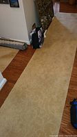 Long beige floor runner laid on hardwood floor, showing nearly full length with subtle floral pattern and plush texture.