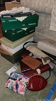 Stack of shoe boxes with various purses and wallets laid out on the floor.