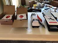 Two boxed red Dash mini waffle makers, Diamond Hone sharpener, and mandoline slicer on countertop.