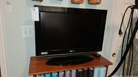 Full view of the Sharp 26-inch TV with base stand on a wooden surface showing front screen and frame.