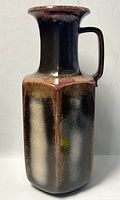 Front angle view showing vase's hexagonal shape, handle, and glazed color gradient from reddish-brown to black.