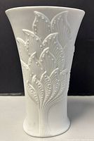 Front view of the white porcelain bisque vase showing the detailed raised leafy branch relief pattern on the body.