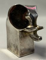 Front view showing the elephant's trunk and stylized ears with reflective silver plated surface and patina.