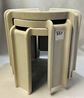 Three beige acrylic SYROCO stacking side tables nested together showing compact stacking design and rounded edges.