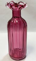 Photo of the cranberry glass vase showing entire vase with ruffled top and ribbed vertical lines on body.