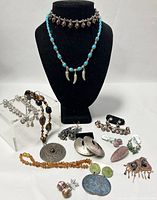 Full lot overview showing necklaces on stand, bracelets, earrings and pins arranged on white surface