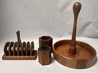 Photo showing four wooden kitchen items: a round serving tray with a tall center handle, a toast rack, and two hexagonal salt and pepper shakers.