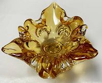 Top view of amber freeform blown glass ashtray or bowl showing scalloped and flowing curved edges with smooth glossy surface and central well.