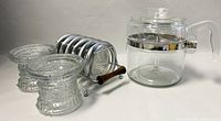 Clear glass Pyrex stovetop coffee percolator, coasters, candleholders and coaster rack arrangement