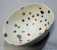 Oval white glass bowl with colorful millefiori motifs scattered inside, shown clearly from above.
