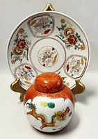 Ginger jar positioned in front of hand-painted plate showing overall decoration of both pieces