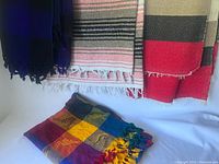 Three blankets, including striped and patchwork designs, displayed with some folded and some stretched out.