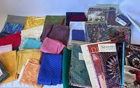 Top view showing various cotton quilting fabric pieces arranged with quilting pattern books on the right.