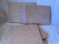 Multiple pine wood blanks of approximately 11 x 14 inches, rectangular with visible natural wood grain, stacked together on a white surface.