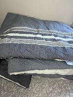 Comforter stacked and folded showing whole item with gray base and white/black stripes