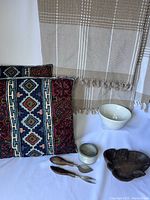 Full view of home decor items including cushions, wall hanging, ceramic bowl, cheese knives, and wooden tray.