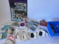 Overview of the jewelry making supplies lot showing storage boxes with multicolored beads, packets of fasteners, and jewelry findings.