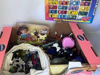 Lot view showing boxed doll with cow figure, diecast cars display card, and various loose plastic animal and toy parts inside box