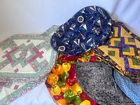 Photo showing six assorted placemats with various quilting patterns and colorful prints including nautical themes, geometric patterns, and produce print.