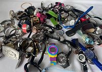 Image showing a wide collection of mixed brand wristwatches including metal and plastic bands, various colors and sizes spread out on a flat surface.