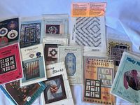 Photo of a mixed collection of printed quilting pattern sheets and booklets, featuring various quilt block designs including seasonal and Christmas themes.