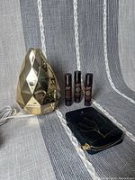 Photo of gold-tone geometric Saje AromaGem diffuser, three roll-on essential oil blends, and black pouch with gold botanical design