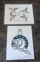 Two prints stacked, one showing four stylized birds in black and gray Haida design and the other showing a stylized orca design