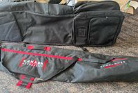 Two ski and snowboard bags laid out side by side showing front and side views. One bag is black padded with external pockets; the other is black canvas with red trim and brands.
