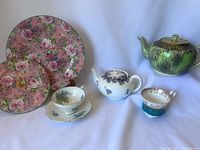 Overview of tea party lot items including teapots, teacups, saucers, and tiered stand