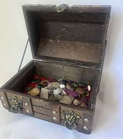 Open wooden chest showing mixed stones inside on red fabric lining.