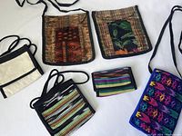 All six items arranged with visible variation in size, color, and design, showing front faces and straps of woven crossbody bags and wallet.