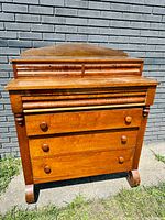 Front view displaying two small top drawers and three larger lower drawers, with round wooden knobs and original finish.