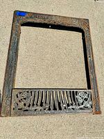 Full view of the entire antique cast iron fireplace insert showing overall shape and pattern.