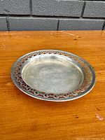 Profile photo showing the round antique sterling silver trinket dish with decorative pierced border and visible glass liner.