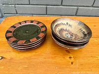 Stack of mid century modern side plates and small bowls on wooden surface, showing geometric pattern and glaze details.
