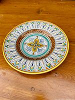 Top view of round vintage Majolica plate with detailed multicolored hand-painted floral and leaf pattern.