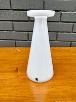 Front angle of white glass vase/candle holder showing tapered shape and label on base